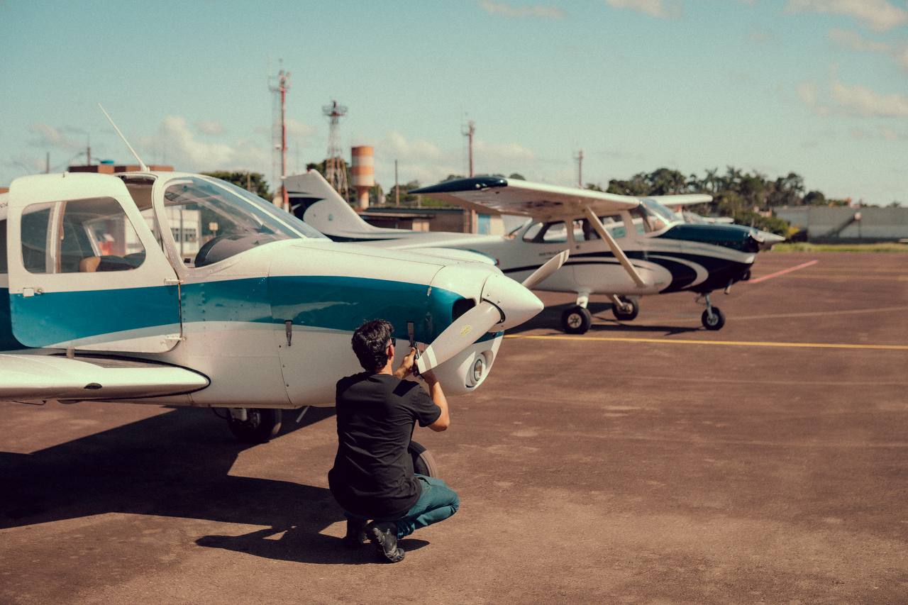 Aluno agachado inspecionando a hélice da aeronave antes do voo